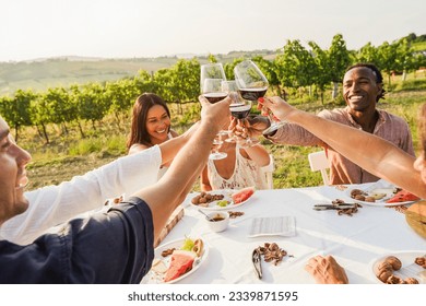 Happy Adult Friends Having Fun Drinking Red Wine And Eating Together With Vineyard In Background   Multiracial People Doing Appetizer At Summer Time In Countryside Resort   Main Focus On Hands