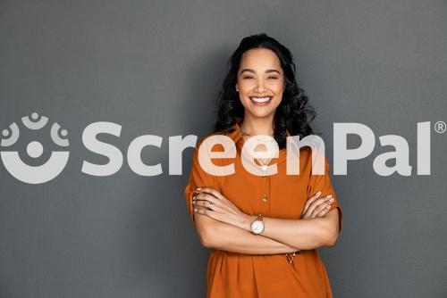 Portrait Of A Young Latin Woman With Pleasant Smile And Crossed Arms Isolated On Grey Wall With Copy Space Beautiful Girl With Folded Arms Looking At Camera Against Grey Wall Cheerful Hispanic Woman