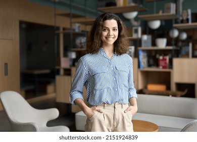 Young Smiling Latin Girl College Student Or Teacher Looking At Camera Standing In University Campus Happy Hispanic Millennial Woman Professional Posing In Modern Coworking Creative Office Space