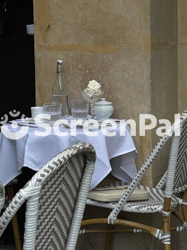 A Table With Two Chairs And A White Tablecloth