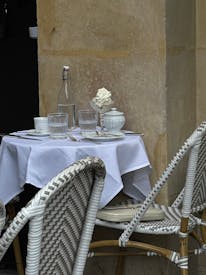 A Table With Two Chairs And A White Tablecloth