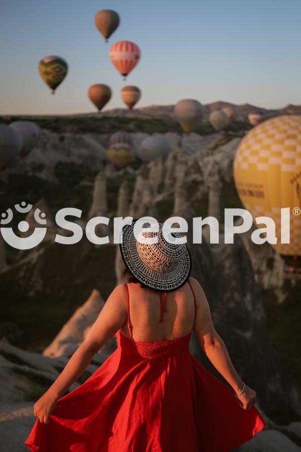 A Woman In A Red Dress Is Looking At Hot Air Balloons