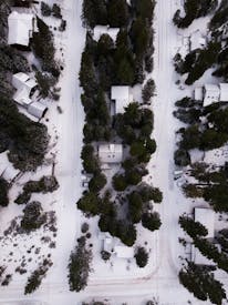 Areal Photography Of Snow Covered Houses Surrounded By Green Trees