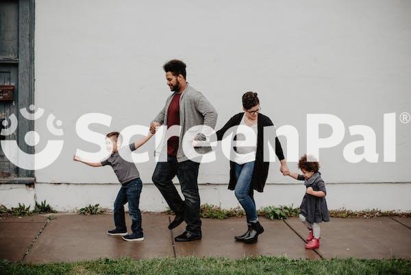 Family Of Four Walking At The Street