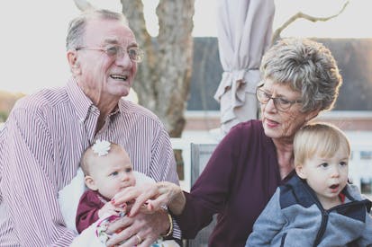 Grandmother And Grandfather Holding Child On Their Lap