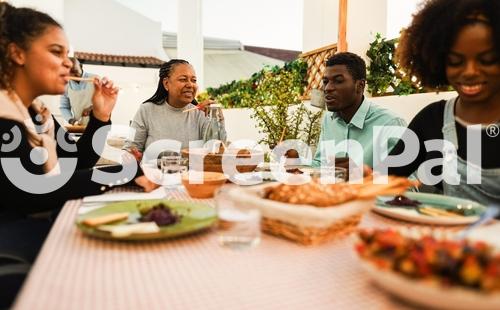 Happy African Family Having Dinner At Home Rooftop Terrace Outdoor   Summer Food And Lifestyle Concept   Main Focus On Mother Face